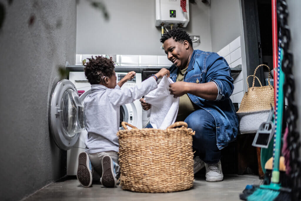 Father and son washing clothes in the laundry at home